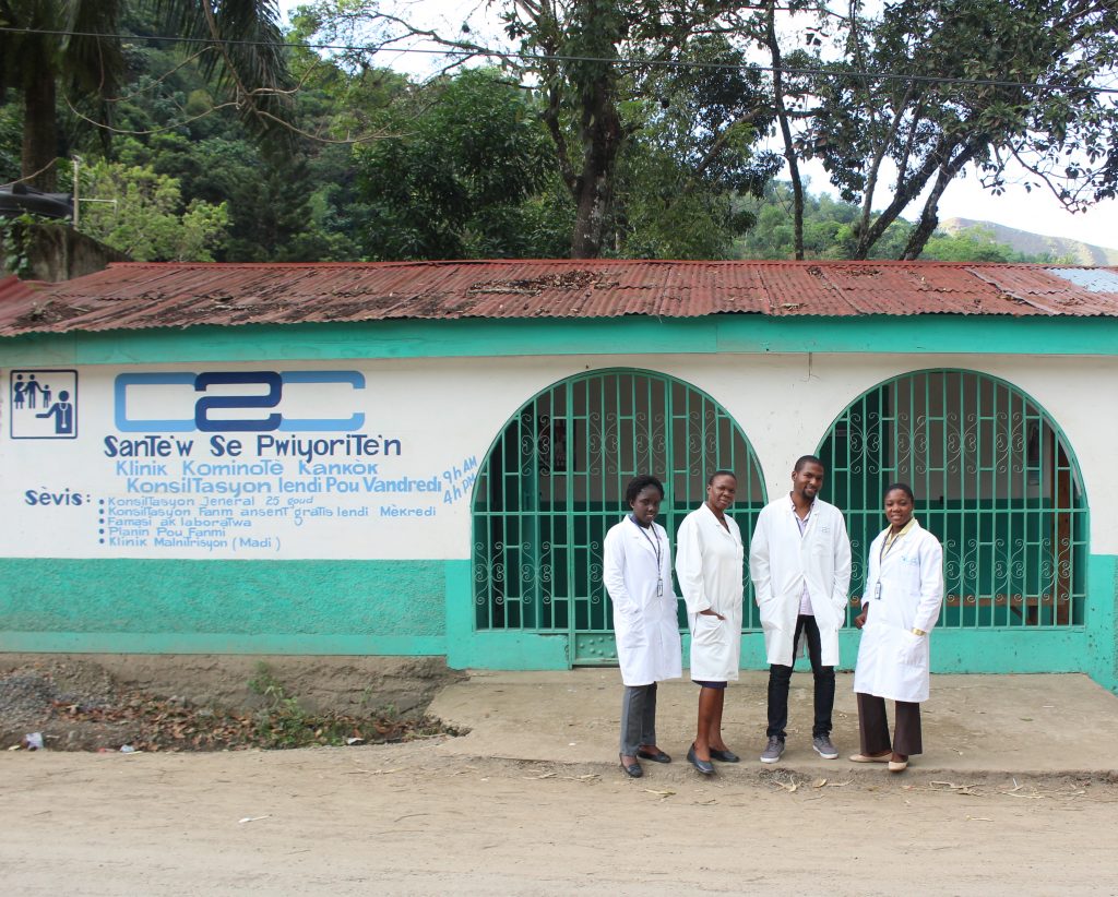 Four practicioners stand outside the Camp Coq clinic